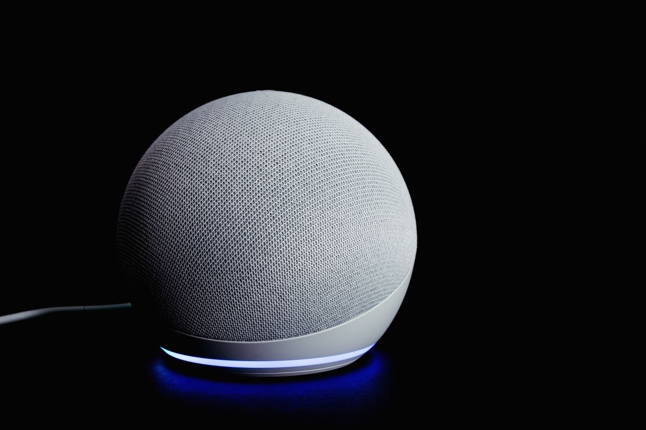 services-01 Appareil d’enceinte intelligente moderne doté d’un anneau lumineux, présenté sur un fond sombre.